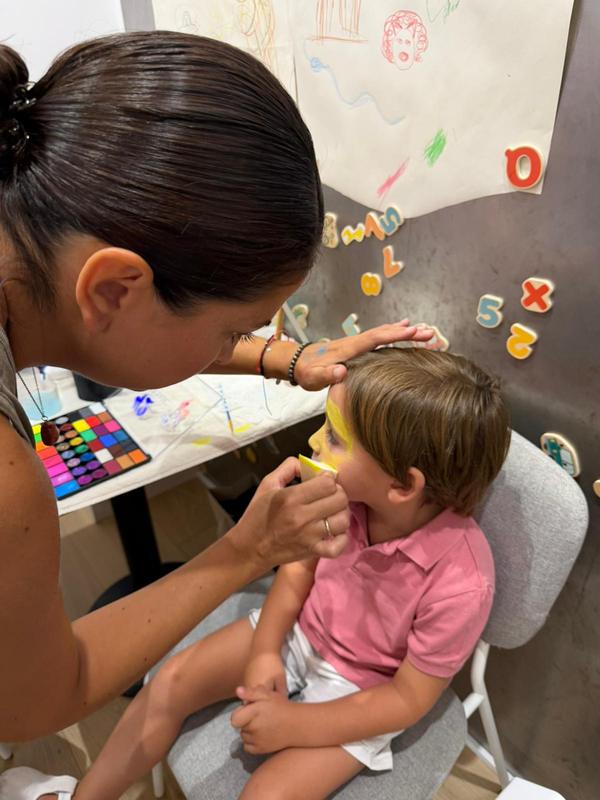 Monitora pintando la cara de un niño como científico