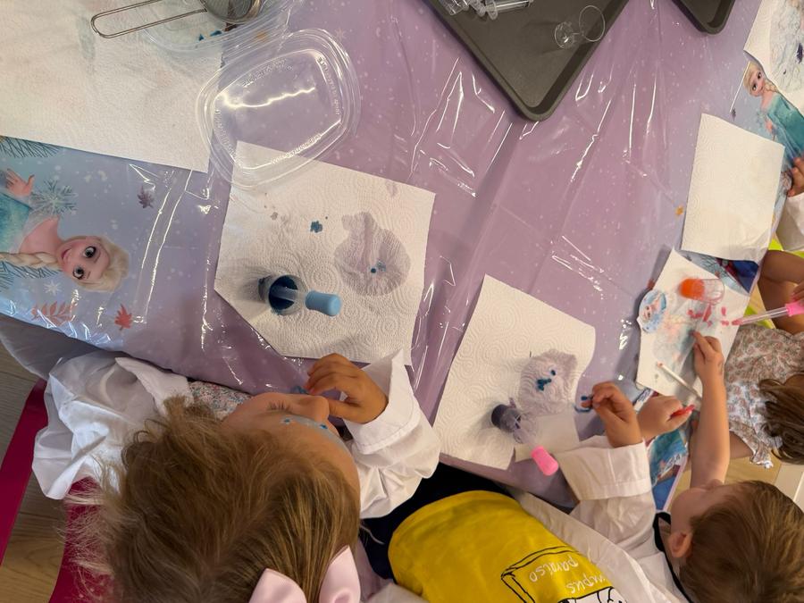 Niños con batas de laboratorio trabajando juntos en un cumpleaños