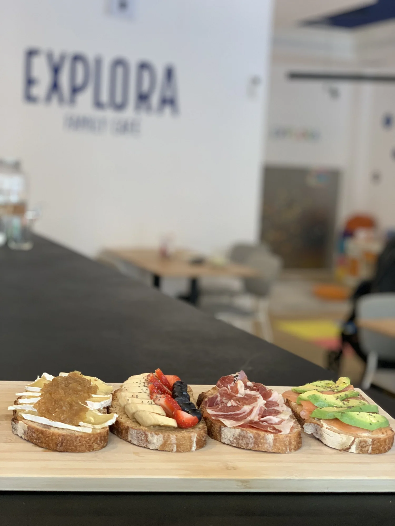 Cuatro tostas sobre una tabla con el rótulo de Explora al fondo